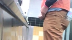 Guys in the urinals taking leak.